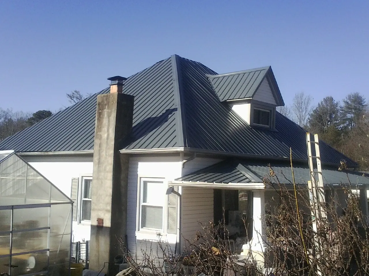 Dark blue standing seam metal roof on a white farmhouse with dormer — Slate & Tile Roof Repair by Roofing Brothers in Escalante