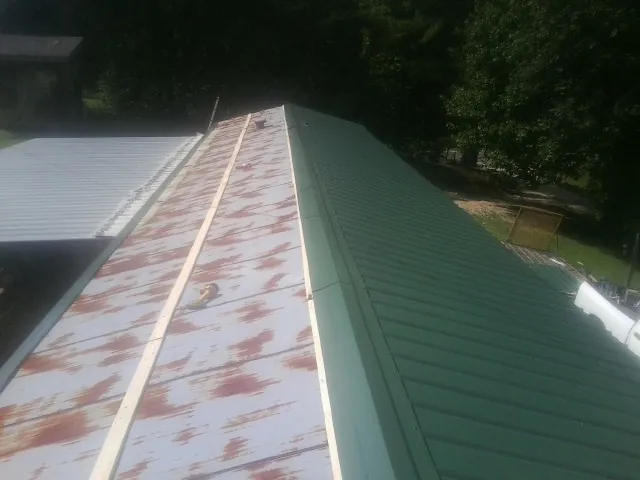 Old rusted panels beside newly installed green metal roofing — Wind Damage Roof Repair by Roofing Brothers in Escalante