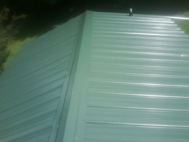 New green metal panels meeting at the ridge of a roof — Flat Roof Repair work by our crew in Escalante