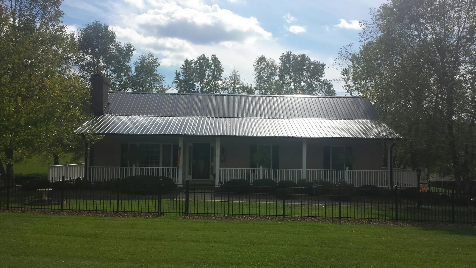 Gray metal roof on a brick ranch with a full width front porch — Gutter Guard Installation work by our crew in Escalante