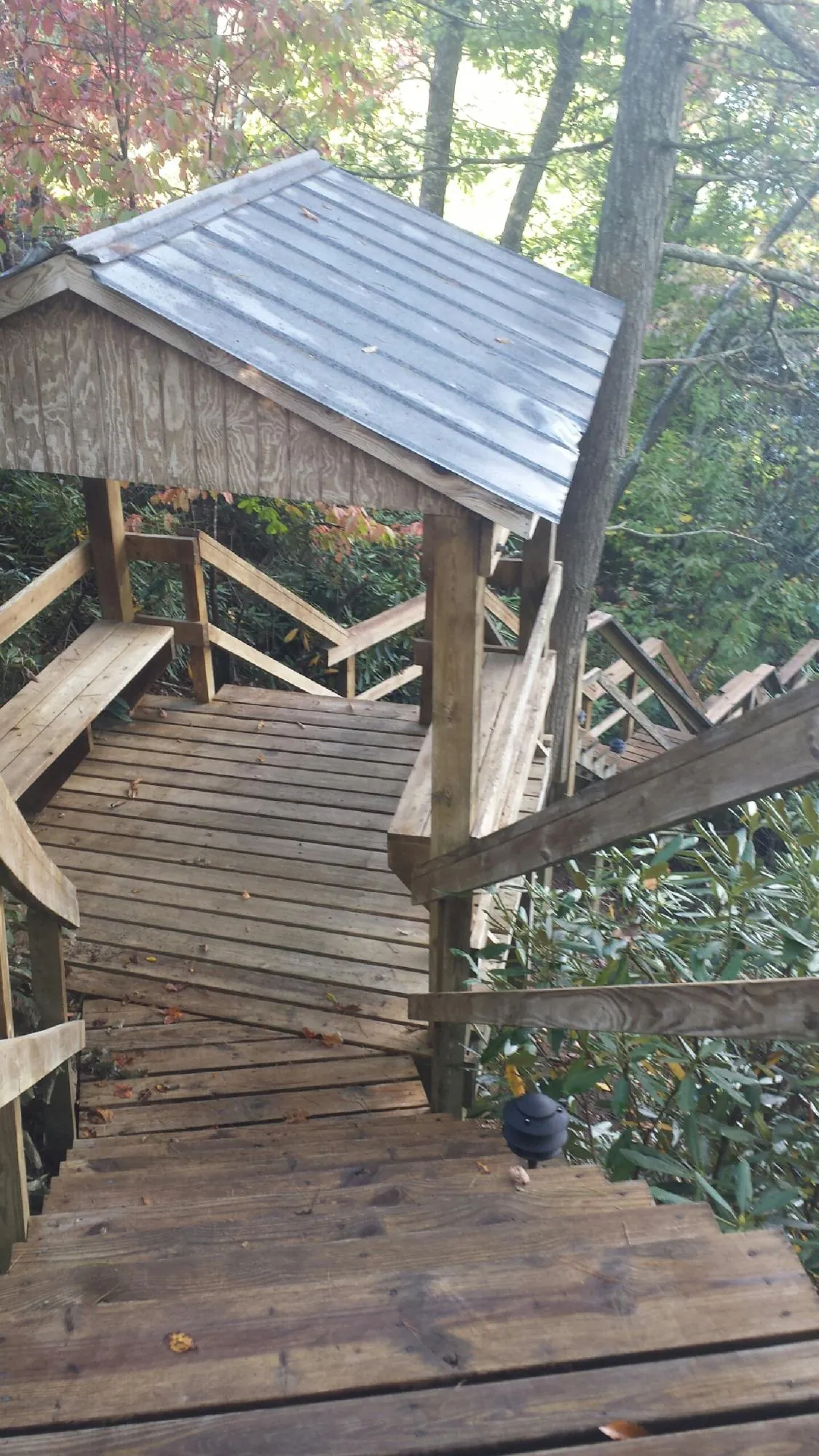 Metal roofed shelter over wooden steps on a wooded walkway — Skylight Repair & Installation work by our crew in Escalante