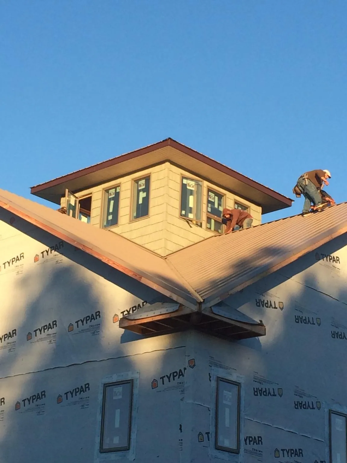 Roofers working around a rooftop cupola on a new metal roof at sunset — Roof Waterproofing in Escalante by Roofing Brothers